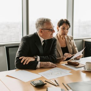 Two business professionals analyzing financial papers in a modern office setting.