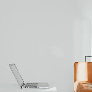Minimalist design featuring a laptop on a white table in a modern home with a leather sofa.