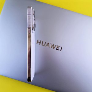 Side view of a smartphone placed on a laptop featuring the Huawei logo on a vibrant yellow background.