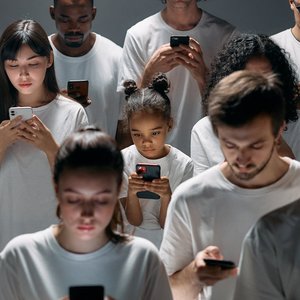 A diverse group of people focused on their smartphones, symbolizing modern technology's impact on social connection.