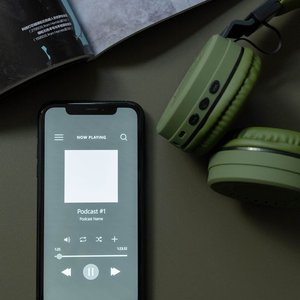 Modern smartphone and green headphones next to a magazine, showcasing technology and lifestyle.