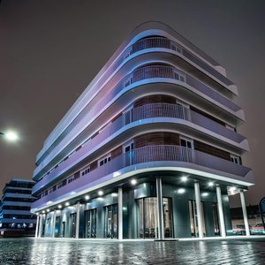 Futuristic modern building illuminated at night in an urban setting.