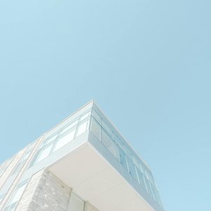 A low-angle shot of a modern building with a glass facade against a bright blue sky in London, Canada.