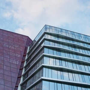 Contemporary urban architecture with glass and red facade against blue sky.
