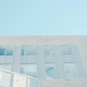 Low angle view of a modern glass facade against a bright blue sky in London, Ontario.