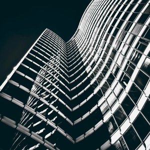 Curvaceous modern skyscraper facade in black and white, highlighting glass and steel elements.