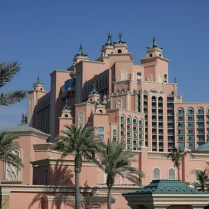 Stunning view of a large pink hotel surrounded by palm trees under a clear blue sky in Dubai.