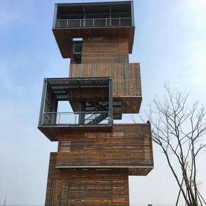 Unique modern wooden tower featuring geometric design and minimalist lines under a blue sky.