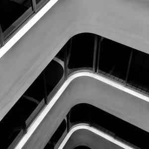 Black and white abstract view of modern architectural building with smooth curves and glass reflections.