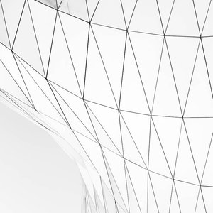 Close-up of a modern glass facade with geometric triangular patterns, showcasing contemporary architectural design.