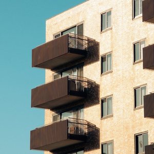 Contemporary brick apartment building with balconies against a clear blue sky.