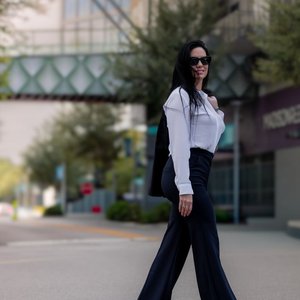 Confident woman in business attire walking on sunny Tampa street.
