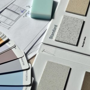Color palette and material samples for interior renovation projects on a blueprint.