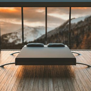 Minimalist bedroom with large windows offering a breathtaking mountain view during sunset.