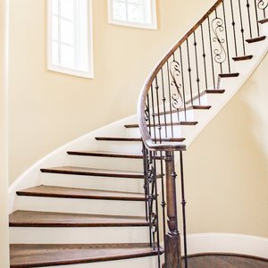 Beautiful spiral staircase with iron railings and wooden steps, lit by natural light.
