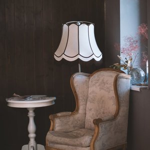 Charming vintage interior with an armchair, elegant lamp, and side table. Perfect for cozy settings.