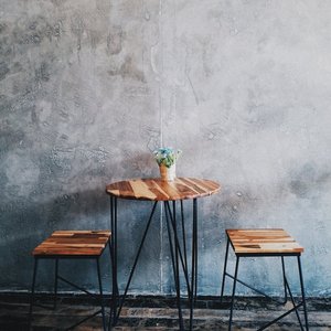 A minimalist wooden table with stools and a concrete wall background, ideal for modern interiors.