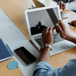 Close-up of a business meeting with laptops and smartphones, focusing on teamwork and digital collaboration.