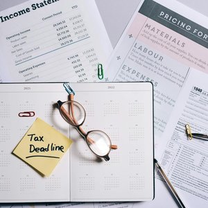 Overhead view of financial documents, planner, and glasses emphasizing tax deadline.
