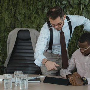 Two businessmen engaged in a collaborative office discussion, using a tablet.