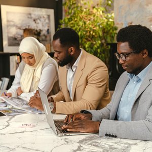 A diverse team discusses ideas at a marble table, brainstorming and planning in an office setting.