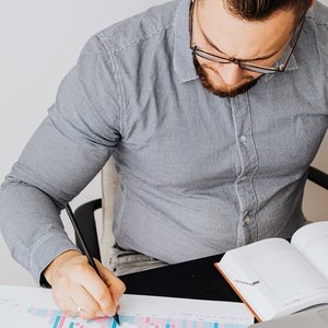 Focused businessman in gray shirt analyzing a financial chart at his office desk, emphasizing data-driven decision making.