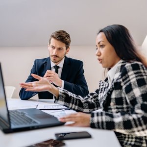 Two business professionals in a meeting discussing ideas in an office.