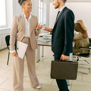 Business professionals conversing in a bright and airy workplace setting.