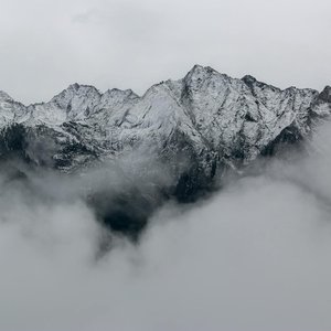 A breathtaking view of snow-covered mountain peaks surrounded by dense fog, creating a mystical landscape.