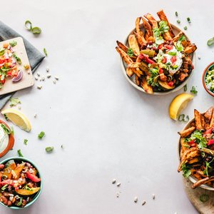Colorful flat lay featuring sweet potato fries, guacamole, and fresh veggies, perfect for a healthy meal.
