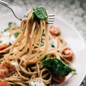 Delicious whole wheat pasta with fresh spinach, cherry tomatoes, and feta cheese in a close-up shot.