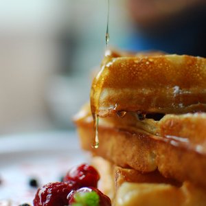 Syrup drips onto stacked waffles with fresh berries, a breakfast delight.