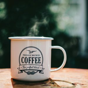 Warm coffee mug steaming on a rustic table, evoking cozy morning vibes.
