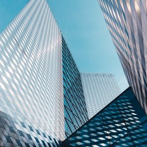 Futuristic skyscrapers in Vilnius with reflective geometric facades under a clear sky.