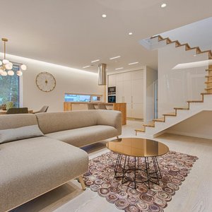 Contemporary living room with neutral tones, a sleek sofa, and elegant wooden staircase.