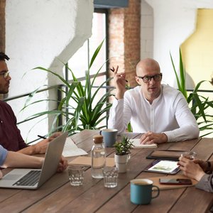 A group of colleagues in a modern office having a strategic discussion around a wooden table.