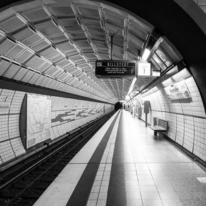 Black and white photo of an empty Hamburg subway tunnel station with urban design.
