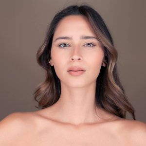 Studio portrait of a beautiful brunette woman with delicate features and a calm expression.