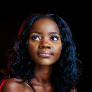 A beautiful portrait of a young black woman with stylish makeup and hairstyle, looking thoughtfully upwards in a studio setting.