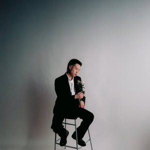 Stylish portrait of a man in a suit holding flowers during a studio photoshoot.