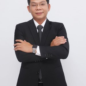 Elegant businessman in a black suit posing confidently with arms crossed in a studio setting.