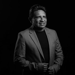 Sophisticated black and white studio portrait of a middle-aged businessman in a formal suit against a dark background.