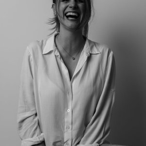 A joyful young woman smiling in a stylish monochrome portrait, captured indoors.