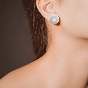 A close-up of an elegant pearl earring on a woman's ear, displaying grace and style.