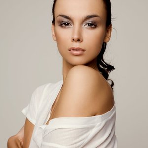 Graceful portrait of a woman in a white shirt, exhibiting a serene and confident expression in a studio setting.