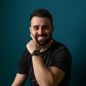 A confident man smiling against a teal background, embodying modern professionalism.
