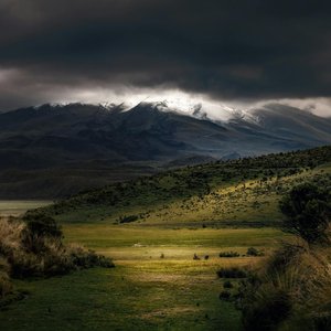 Stunning mountain landscape with dramatic dark clouds and green terrain.