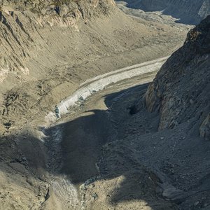 Dramatic aerial shot of a rocky mountain valley with exposed layers and geological features.