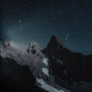 Breathtaking view of a rocky mountain peak under a starry night sky, perfect for wallpapers.