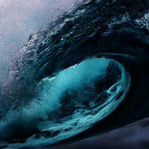 Dramatic capture of a powerful ocean wave with dark blue tones.